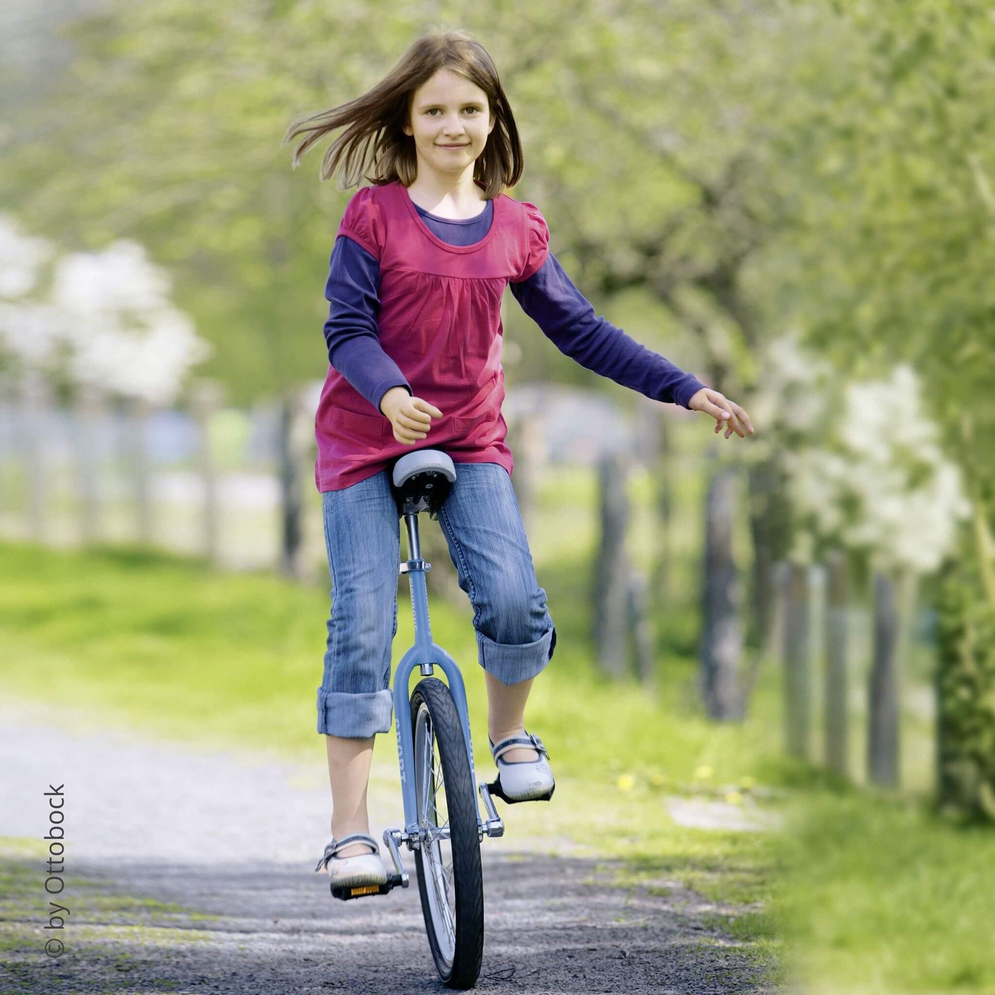 Ein Mädchen mit Armprothese fährt Einrad