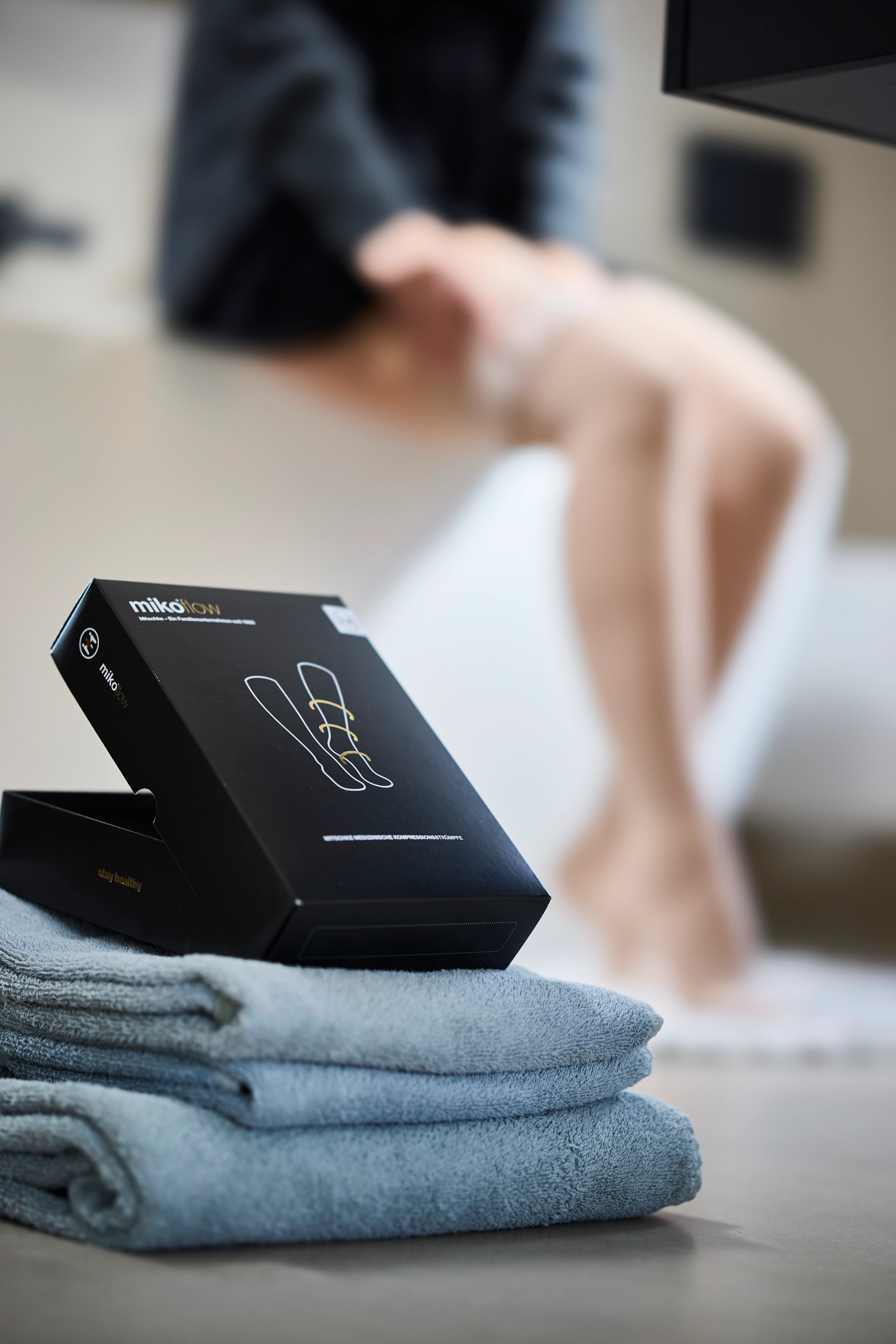 Zwei lachende Frauen in einer Töpferwerkstatt, bekleidet mit Schürzen und farbigen Kompressionsstrumpfhosen in Dip-Dye-Optik.