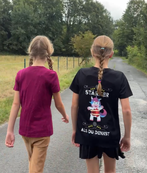 Mila und Hannah gehen einen Feldweg entlang
